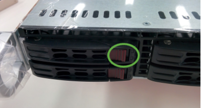 Pushing in the red switch on a USM appliance disk drive.
